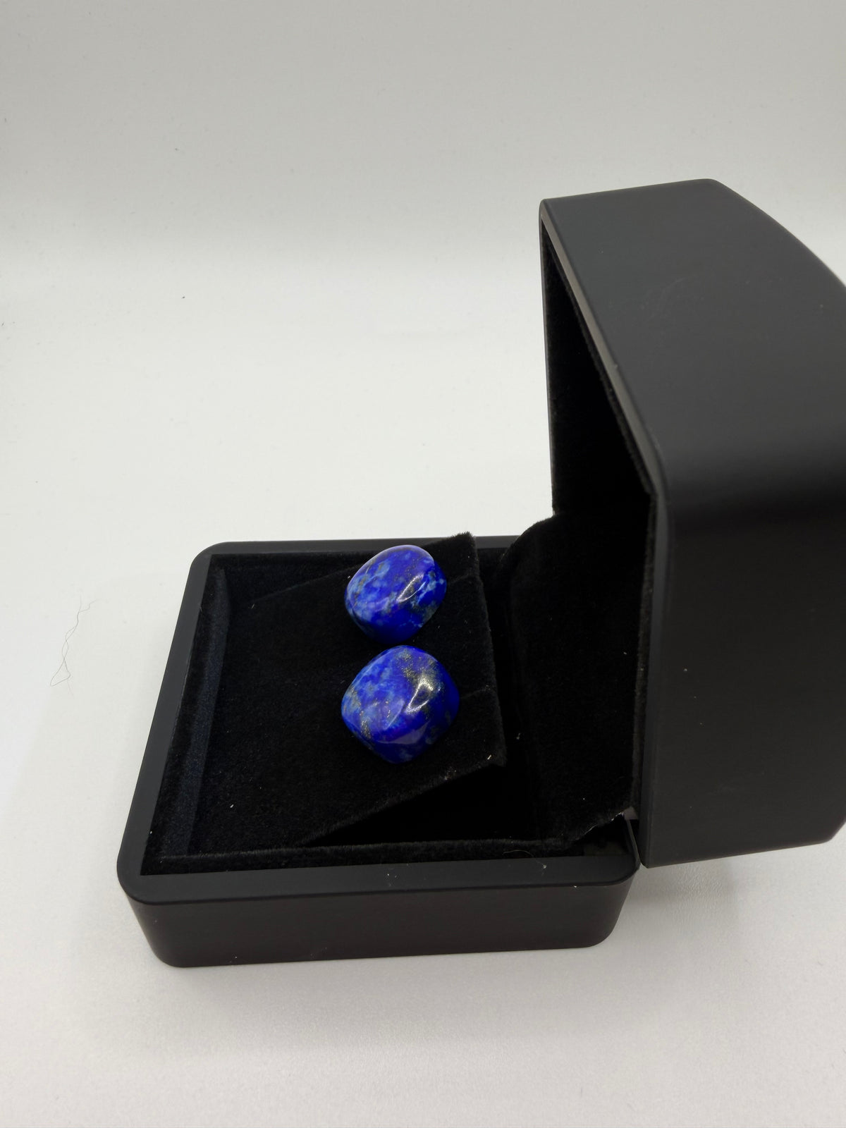 Side view of 30tcw lapis lazuli oval cabochon stud earrings on titanium posts in black gift box, handcrafted in Maine