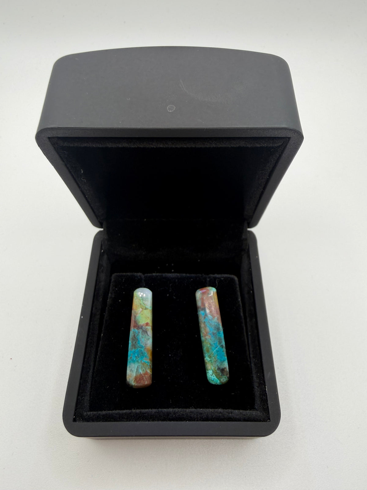 18tcw Namibian Quantum Quattro elongated bar cabochon stud earrings in vivid teal, terracotta, and yellow-green, displayed in open black jewelry box
