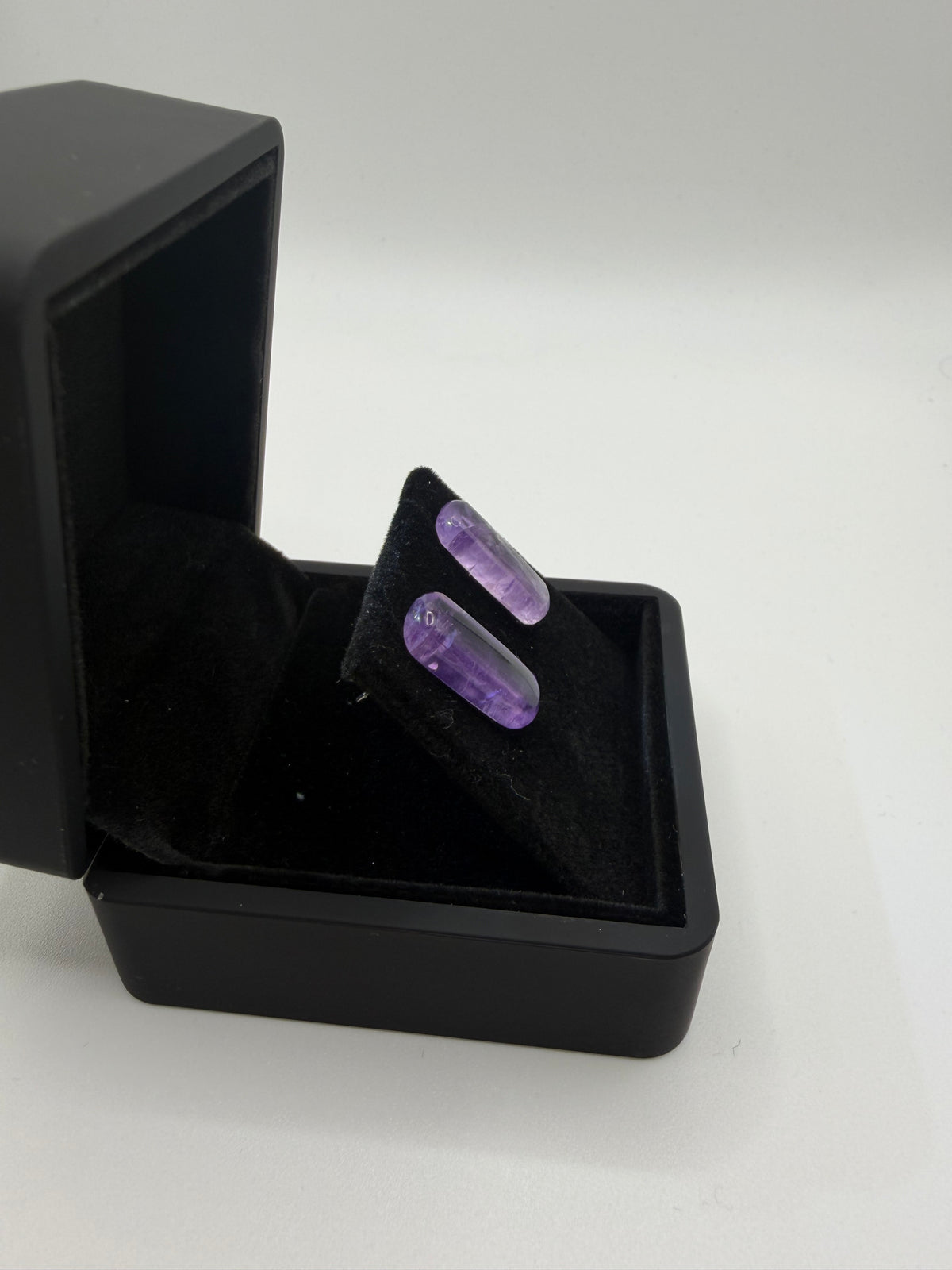 Opposite side view of polished Rwandan amethyst bar cabochon earrings showing their curved profiles.