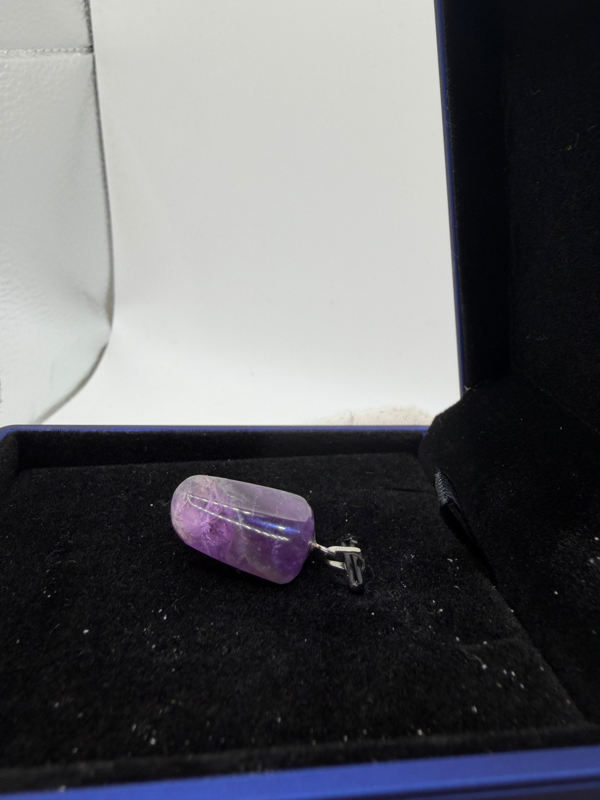 Handcrafted Rwandan amethyst pendant close-up showing natural stone color and sterling silver setting