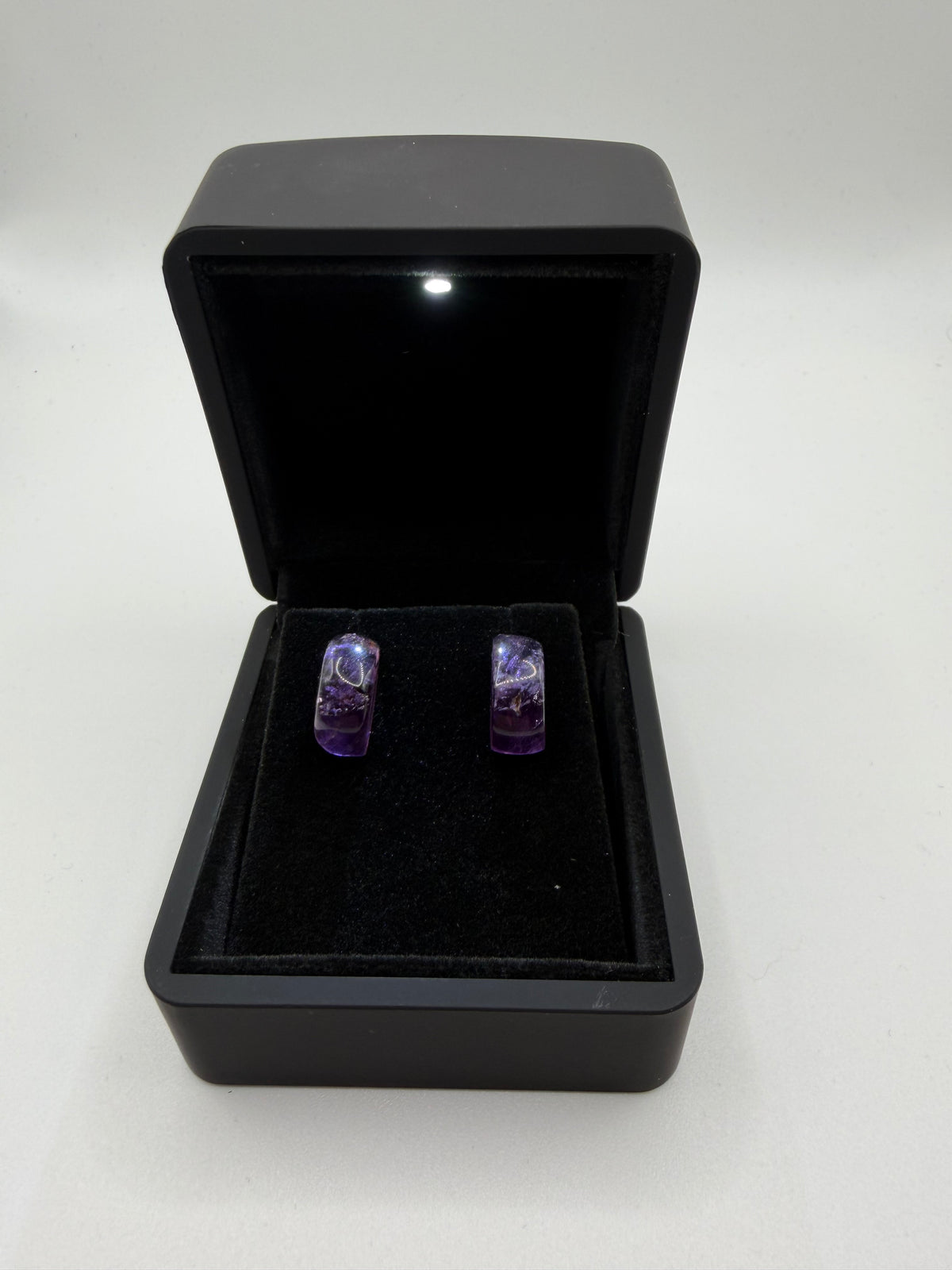 14tcw Rwandan amethyst stud earrings in soft violet-purple rectangular cabochon cut, displayed in open black jewelry box