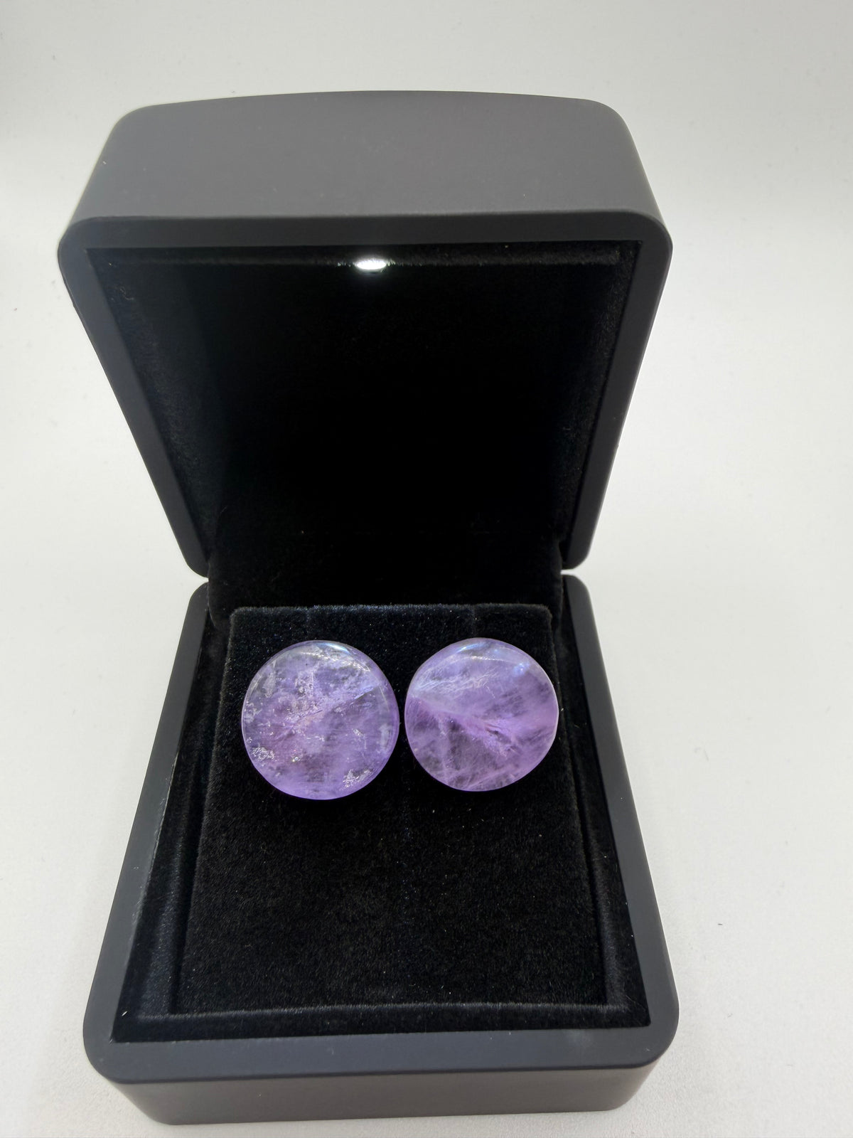 Front view of oval Rwandan amethyst stud earrings showing lavender color and ice-like internal patterns