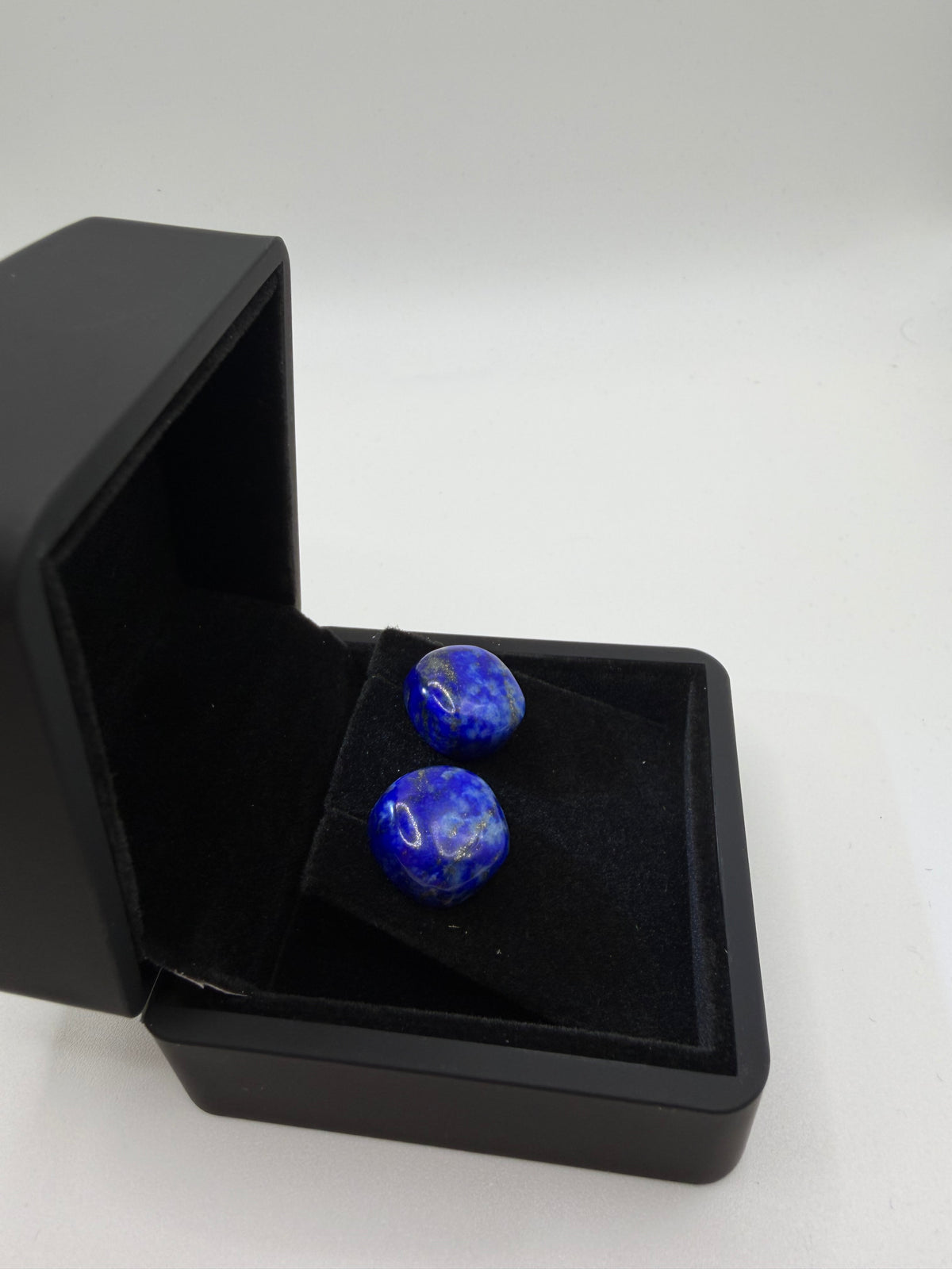 Natural lapis lazuli stud earrings in deep royal blue with white calcite veining, displayed in open black jewelry box