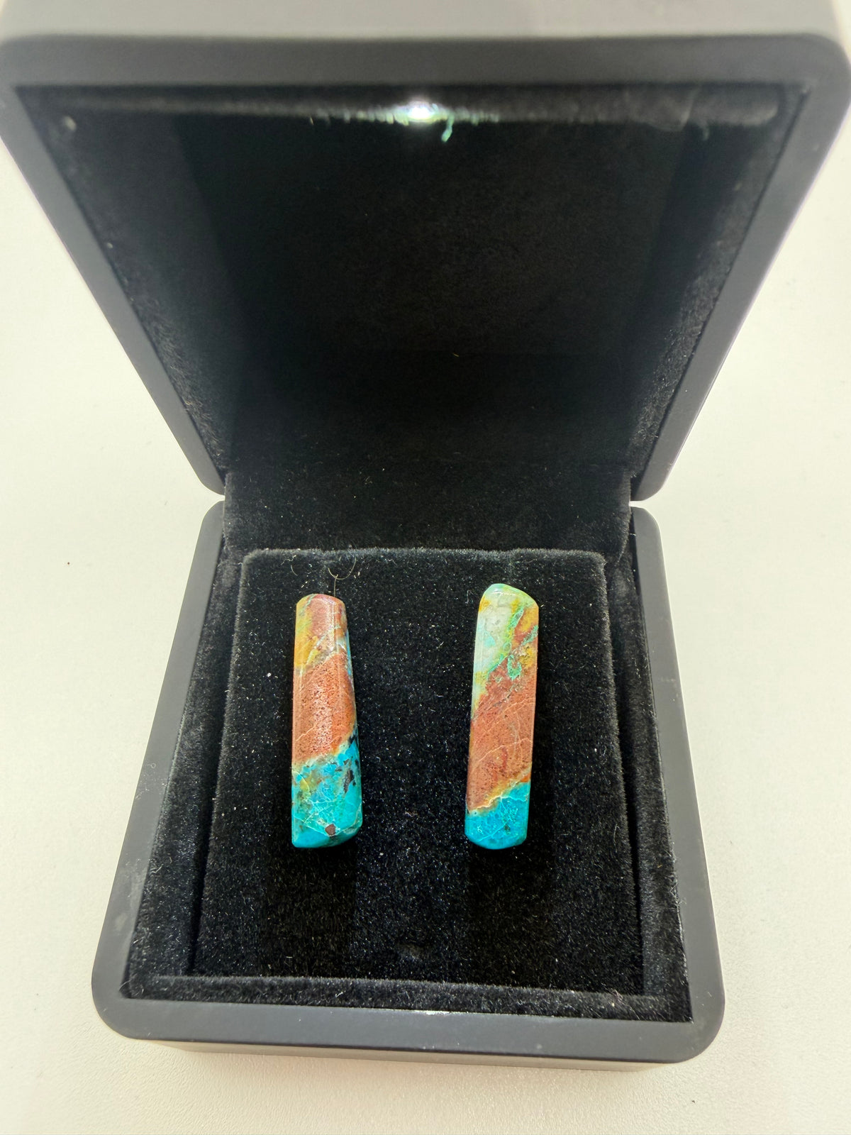 18tcw Namibian Quantum Quattro bar cabochon stud earrings with bold banded terracotta and teal pattern, displayed in open black jewelry box