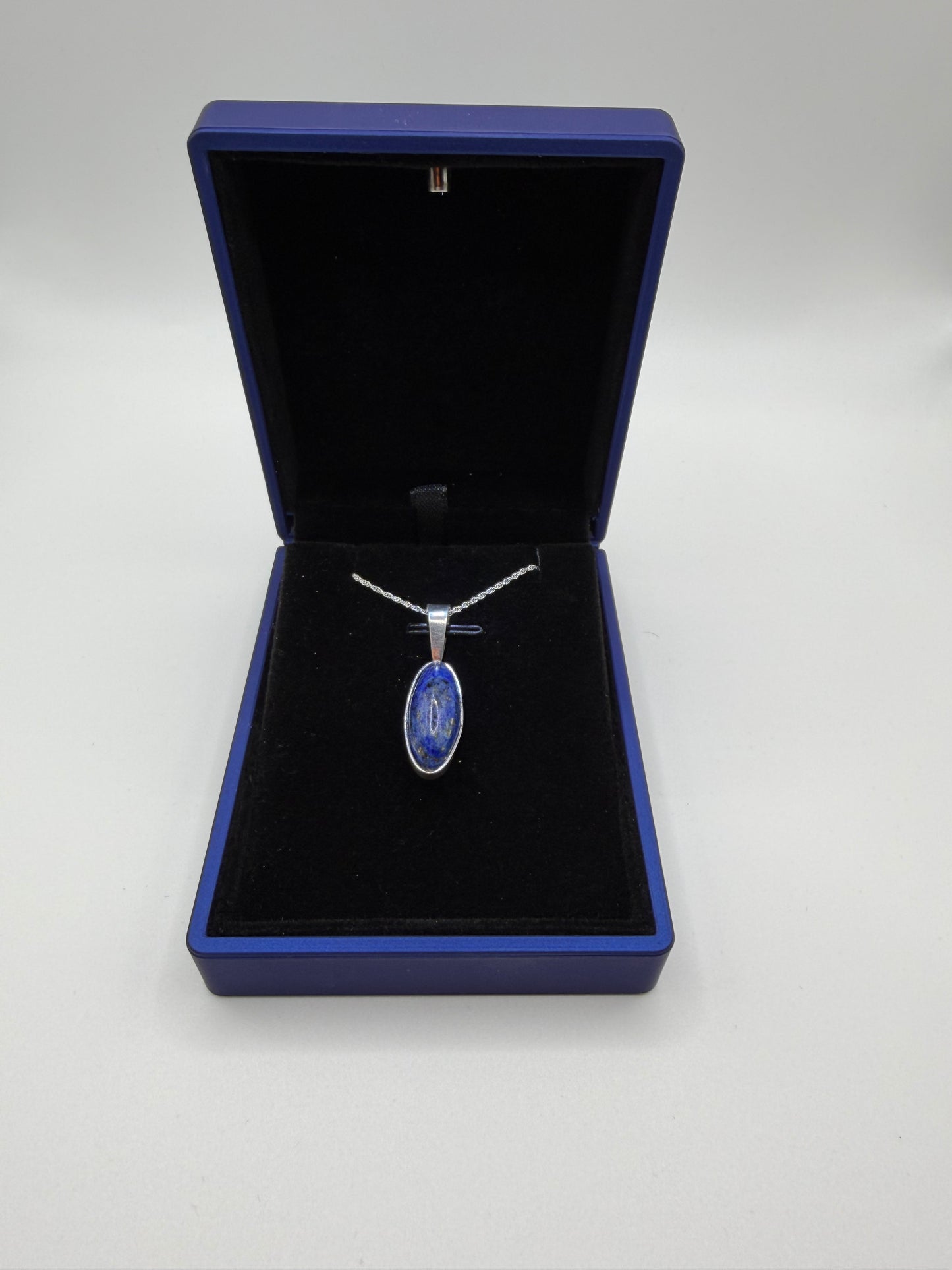 Close-up of slender oval lapis lazuli cabochon showing deep blue color and golden pyrite flecks