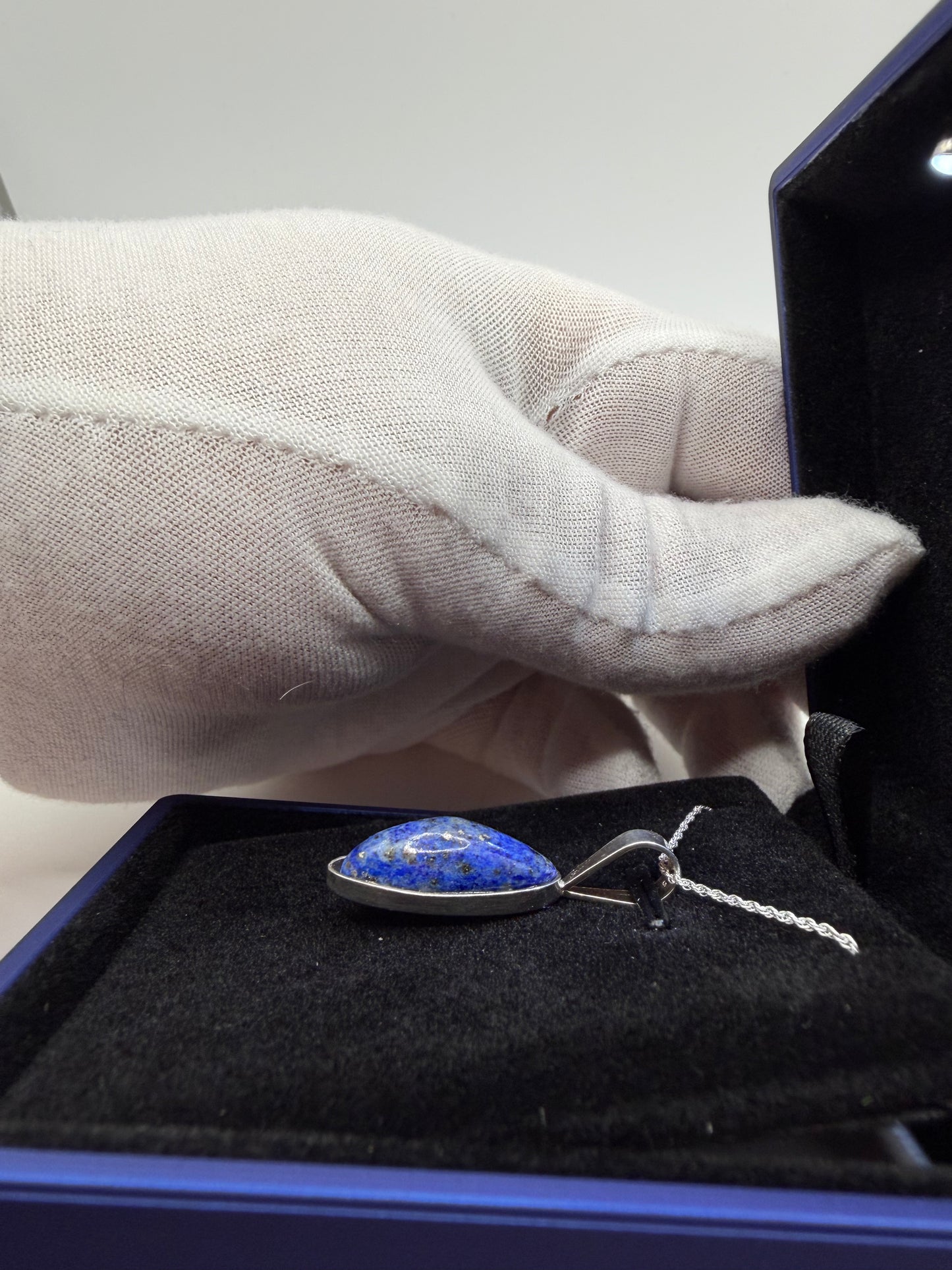 Natural untreated lapis lazuli stone in slender oval shape set in sterling silver pendant with chain handcrafted in Maine