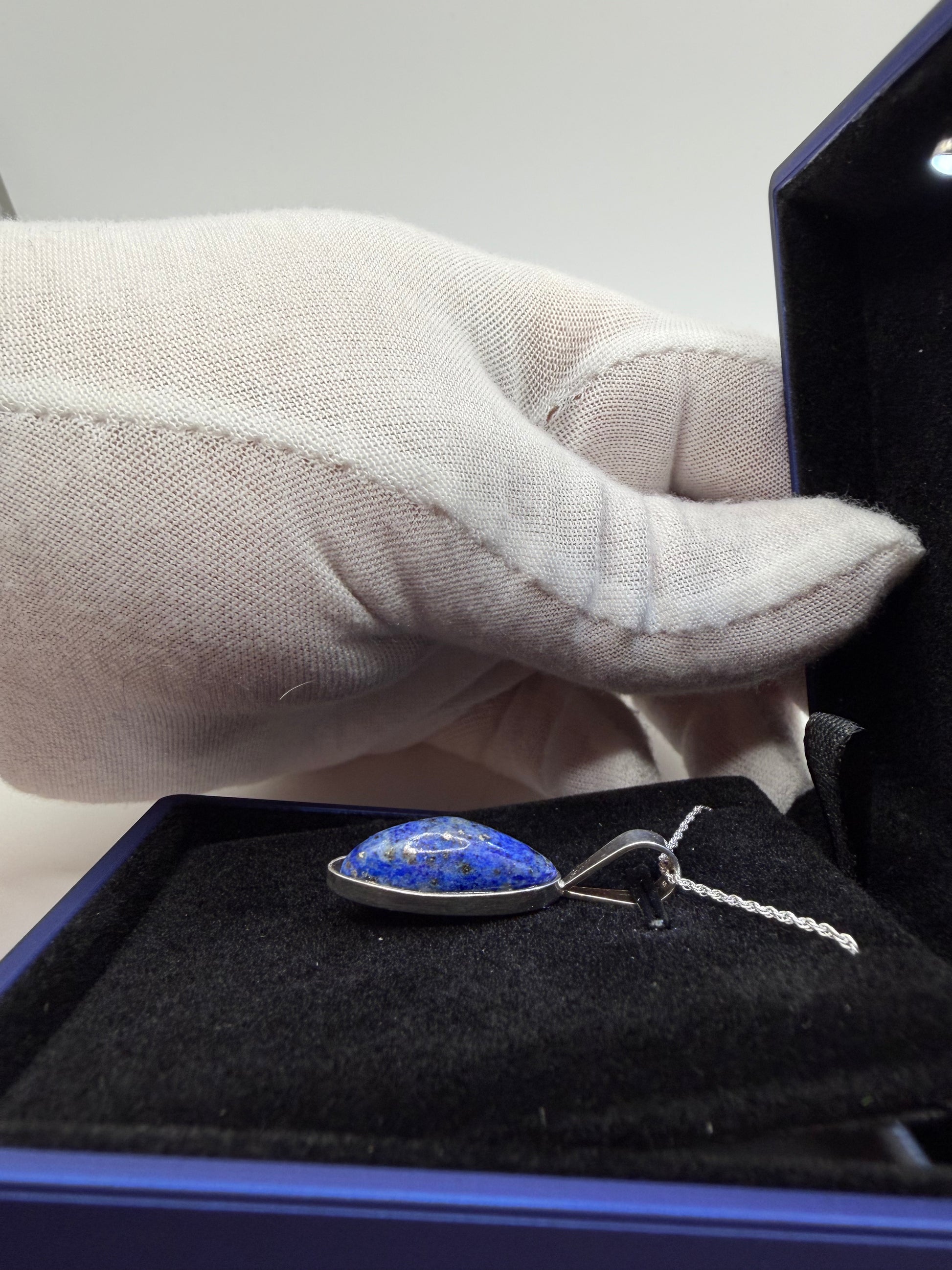 Natural untreated lapis lazuli stone in slender oval shape set in sterling silver pendant with chain handcrafted in Maine