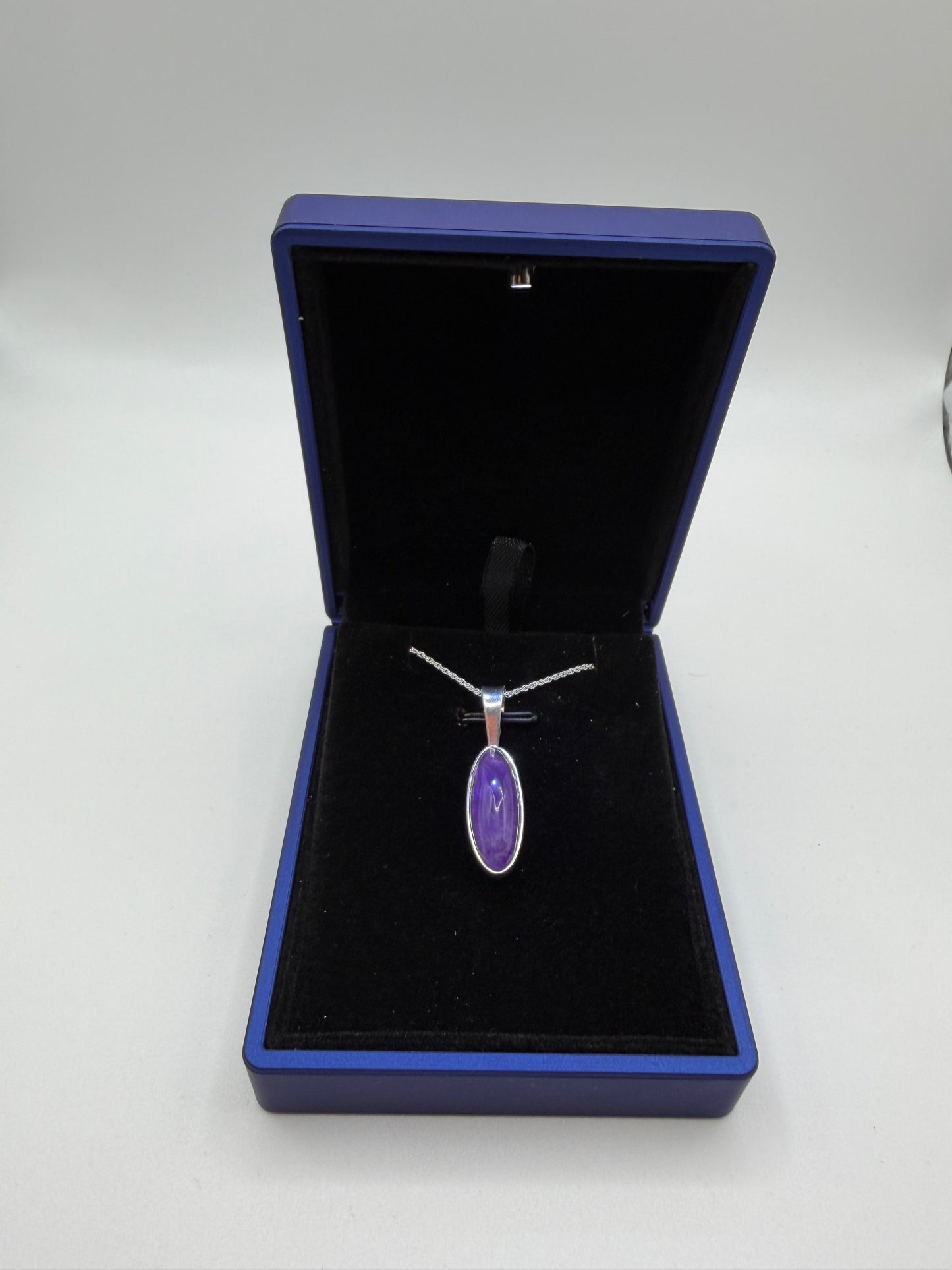 Close-up of slender oval Rwandan amethyst cabochon showing deep purple color and natural clarity