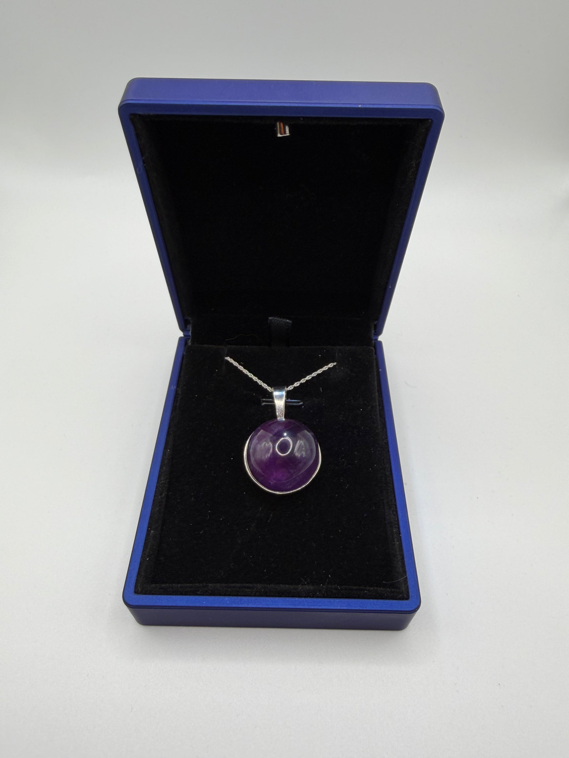 Close-up of 20mm natural Rwandan amethyst cabochon showing deep purple color and clarity