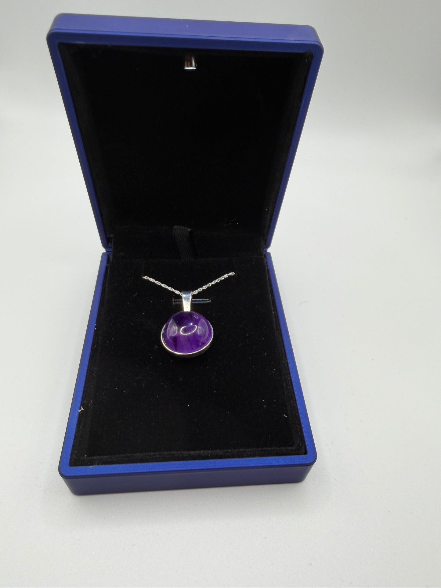 Close-up of 16mm natural Rwandan amethyst cabochon showing deep purple color and clarity