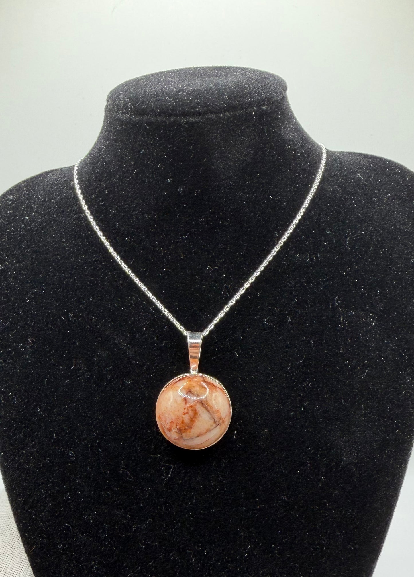 This 20mm Hartland Carnelian is hand-collected from my own raw land in Hartland, Maine. The translucent chalcedony has warm brown-orange tones with natural iron-rich patterns and subtle veining that catch light nicely. It’s untreated, one-of-a-kind, and set in sterling silver — no two pieces are ever the same.
•  Size: 20mm cabochon
•  Stone: Natural Hartland Carnelian (translucent chalcedony, iron-rich, untreated)
•  Setting: Sterling silver bail and chain
•  Sourced & handcrafted in Maine — truly one-of-a