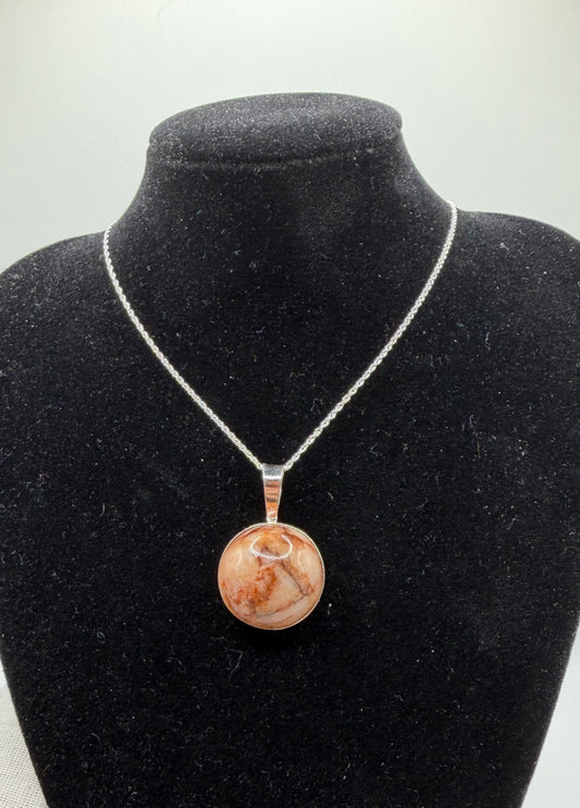 This 20mm Hartland Carnelian is hand-collected from my own raw land in Hartland, Maine. The translucent chalcedony has warm brown-orange tones with natural iron-rich patterns and subtle veining that catch light nicely. It’s untreated, one-of-a-kind, and set in sterling silver — no two pieces are ever the same.
•  Size: 20mm cabochon
•  Stone: Natural Hartland Carnelian (translucent chalcedony, iron-rich, untreated)
•  Setting: Sterling silver bail and chain
•  Sourced & handcrafted in Maine — truly one-of-a